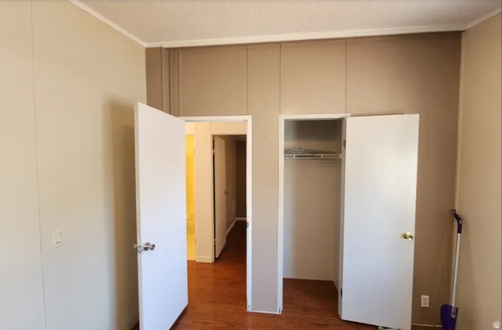 Unfurnished bedroom featuring dark wood-type flooring, a textured ceiling, and a closet