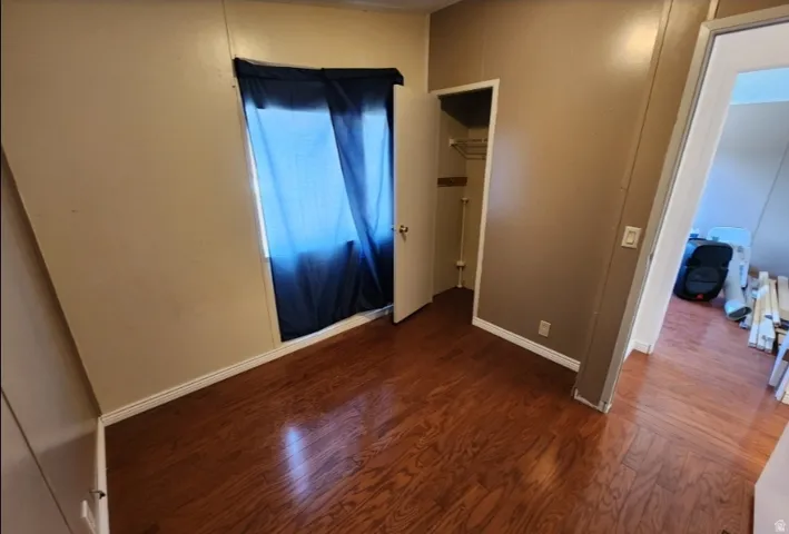 Unfurnished bedroom with dark wood-type flooring and baseboards