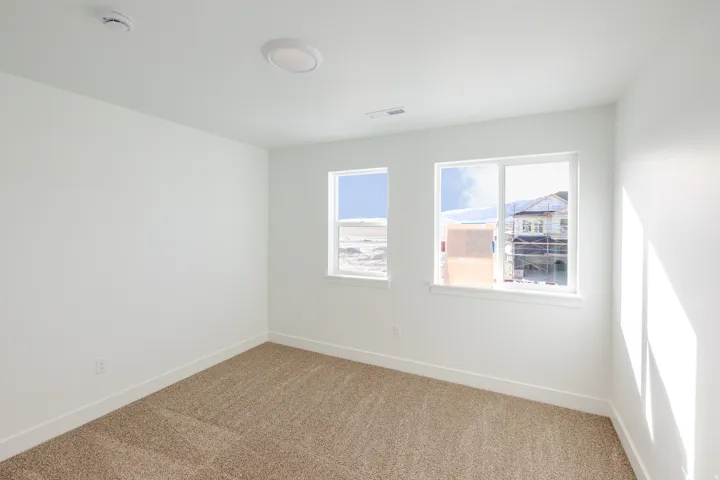 Carpeted empty room with baseboards and a smoke detector