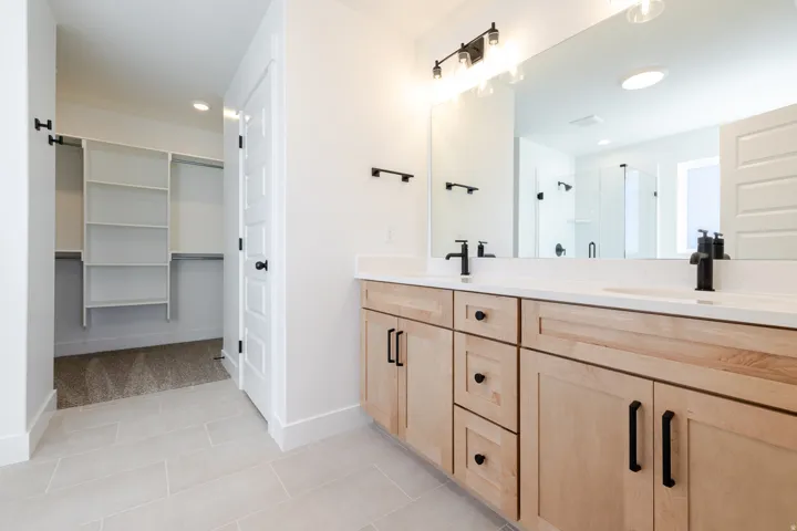 Bathroom with double vanity, a shower stall, a spacious closet, light tile patterned flooring, and recessed lighting