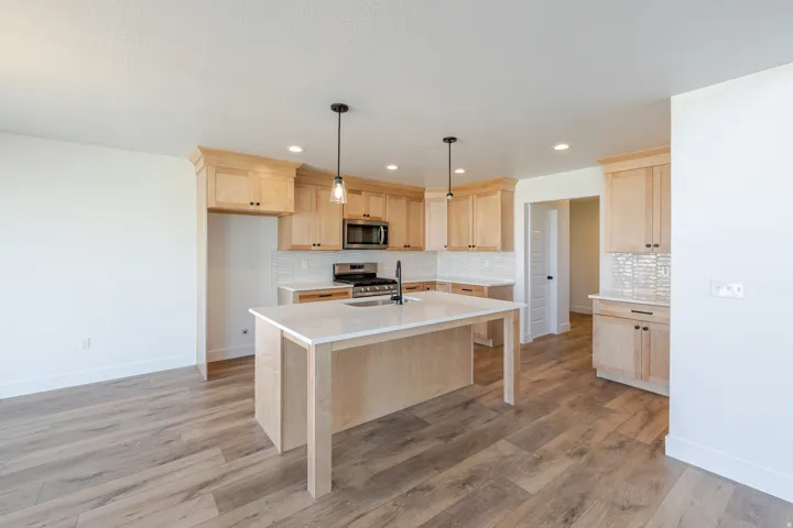 Kitchen featuring light wood finish cabinetry, a kitchen island with sink, stainless steel appliances, and light wood-style flooring