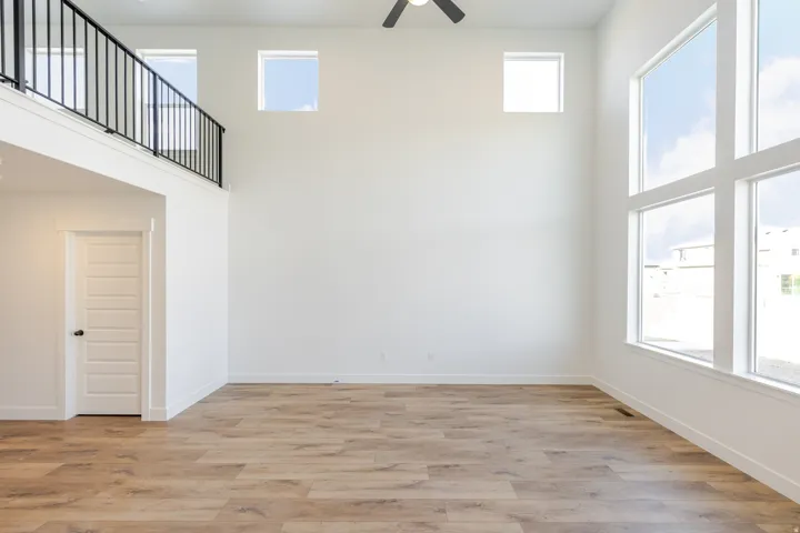 Empty room featuring a high ceiling, light wood finished floors, and a ceiling fan