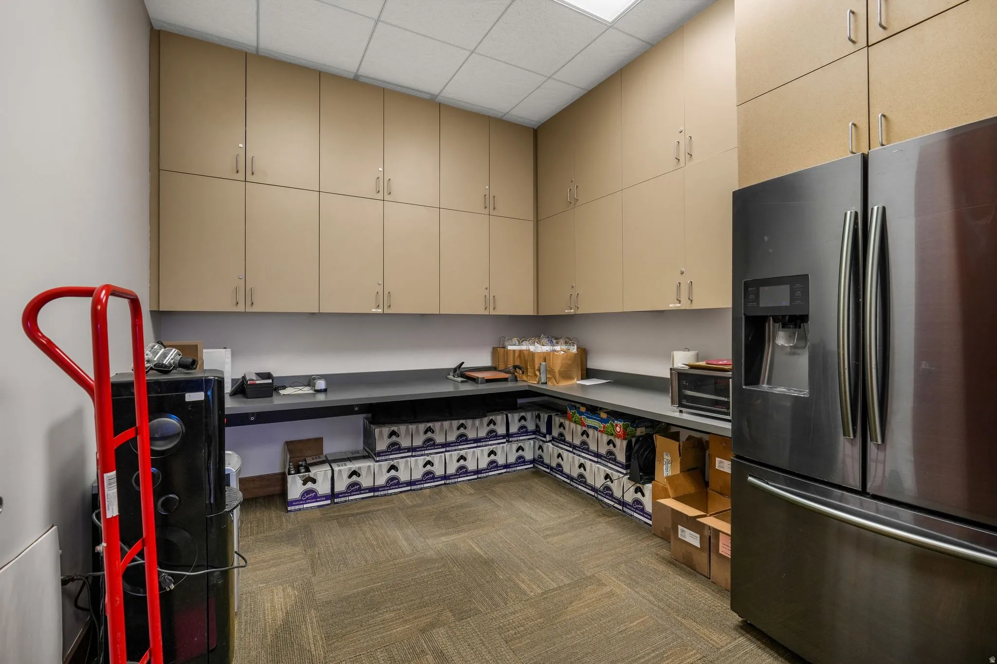 Kitchen featuring stainless steel refrigerator with ice dispenser, a paneled ceiling, dark colored carpet, and cream cabinetry