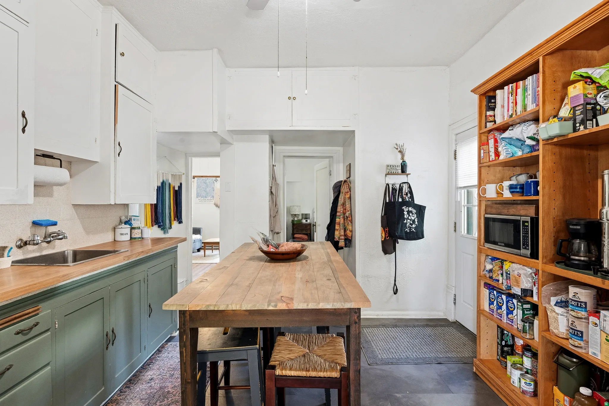 Kitchen with green cabinets, white cabinets, tasteful backsplash, stainless steel microwave, and wood counters