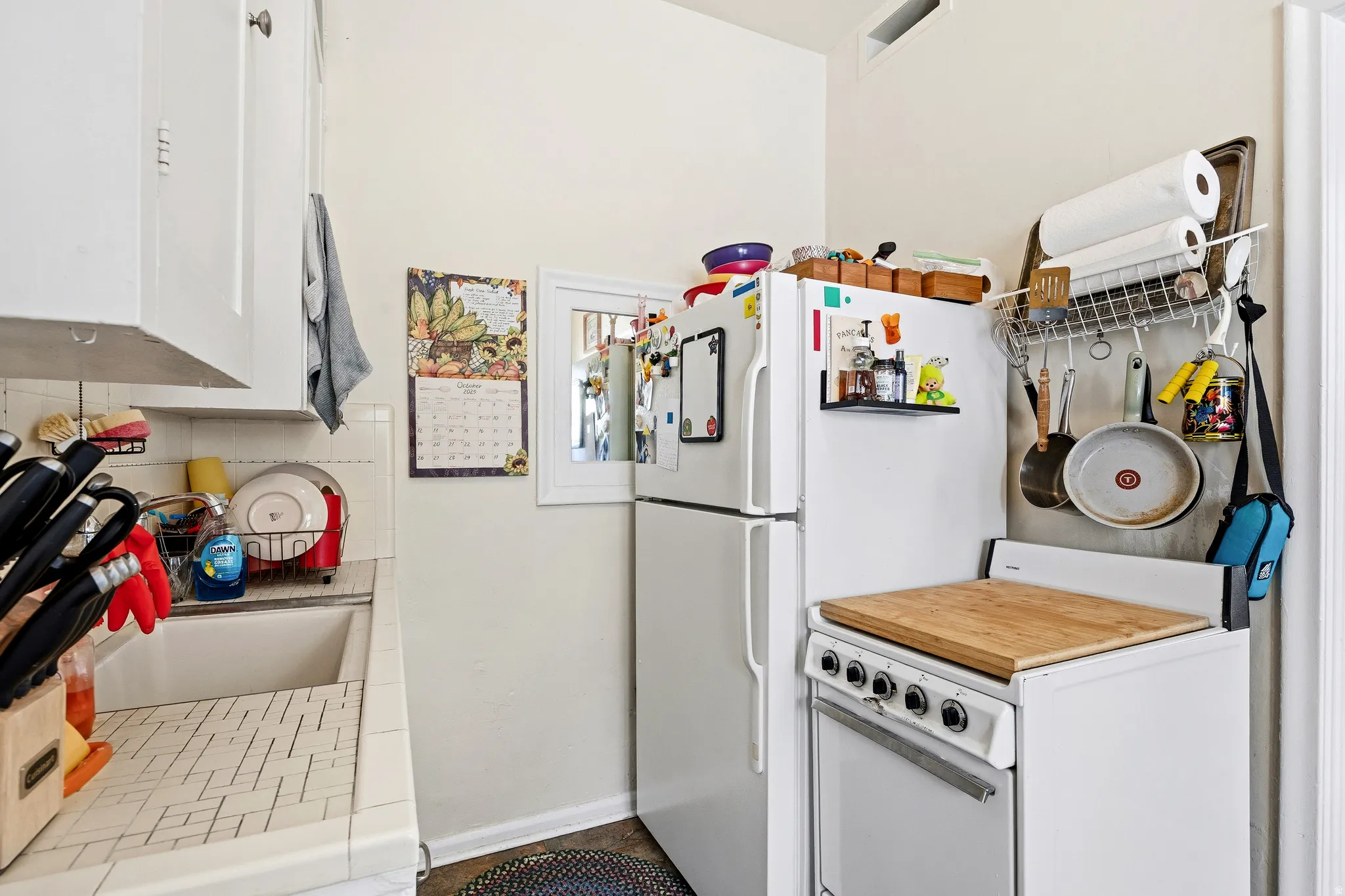 Kitchen with tile counters, white cabinets, and freestanding refrigerator