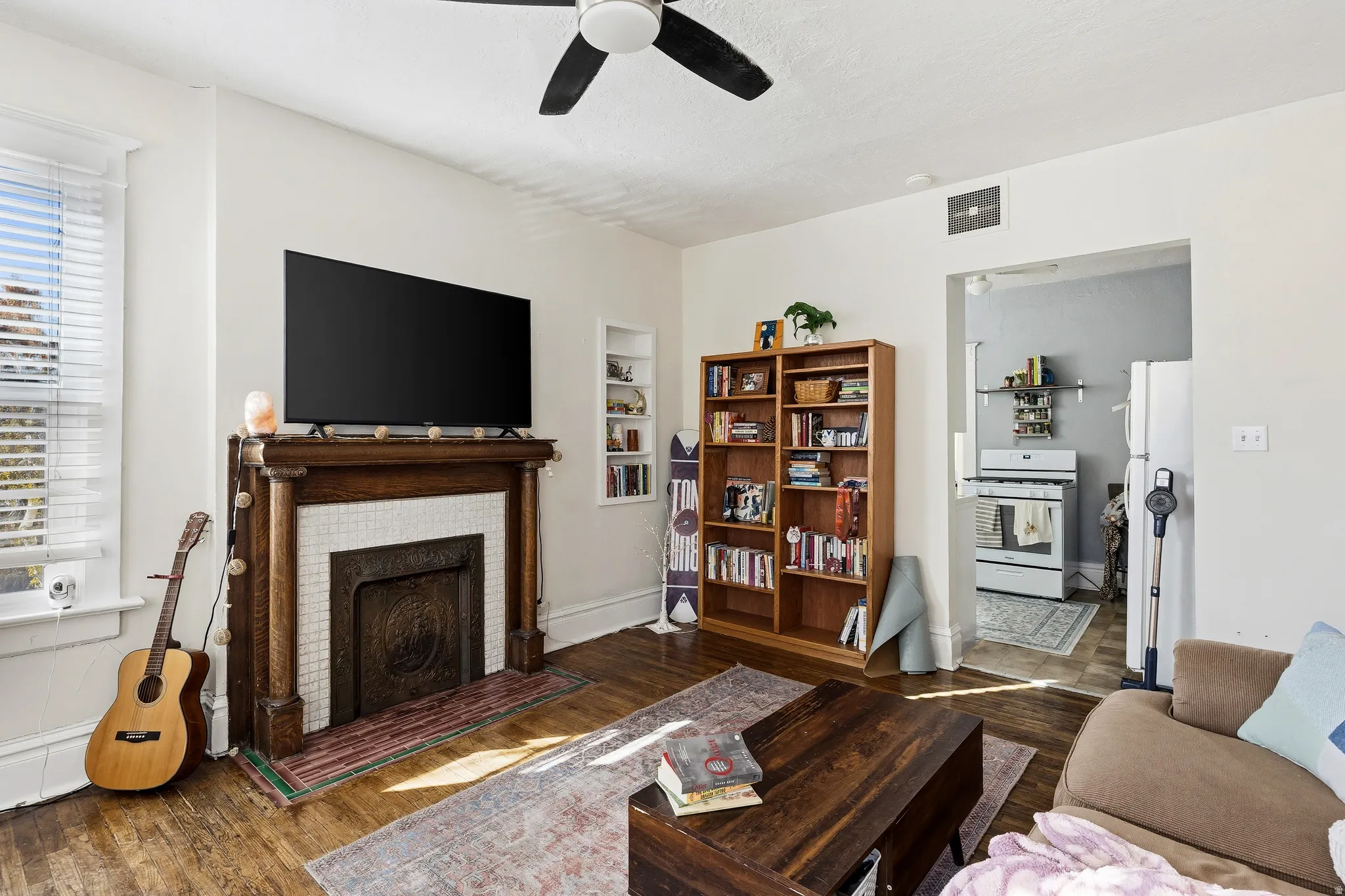 Living room featuring wood finished floors, a fireplace, and a ceiling fan