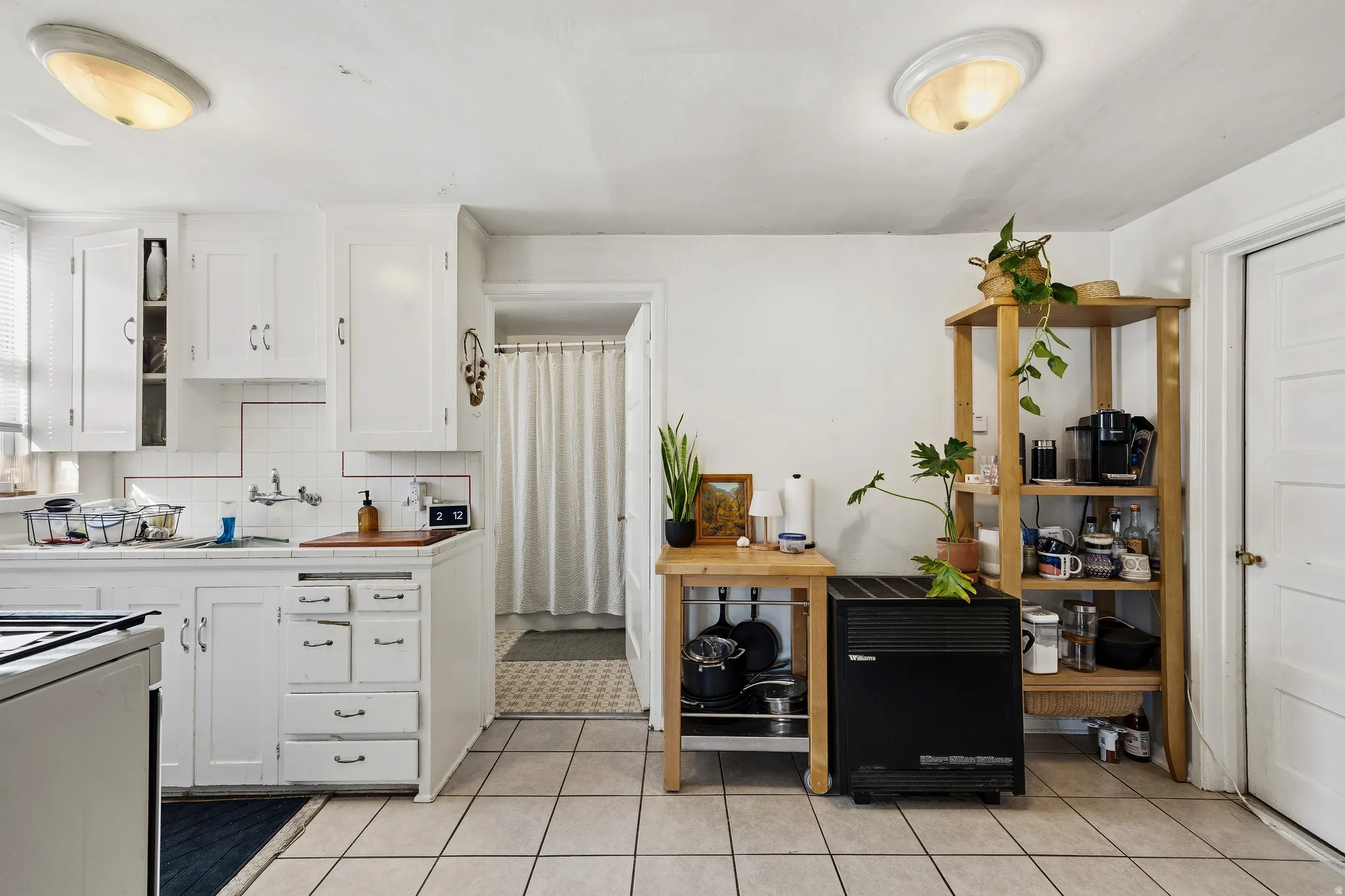 Kitchen featuring white cabinetry, light tile patterned floors, backsplash, and light countertops