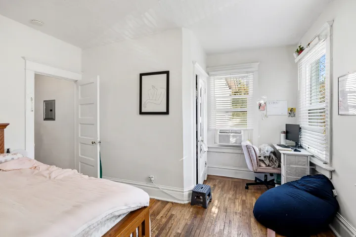 Bedroom featuring dark wood-style floors, an office area, and electric panel