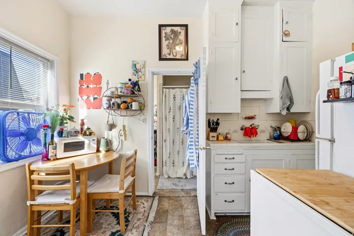Kitchen featuring white cabinetry, decorative backsplash, tile counters, and white appliances