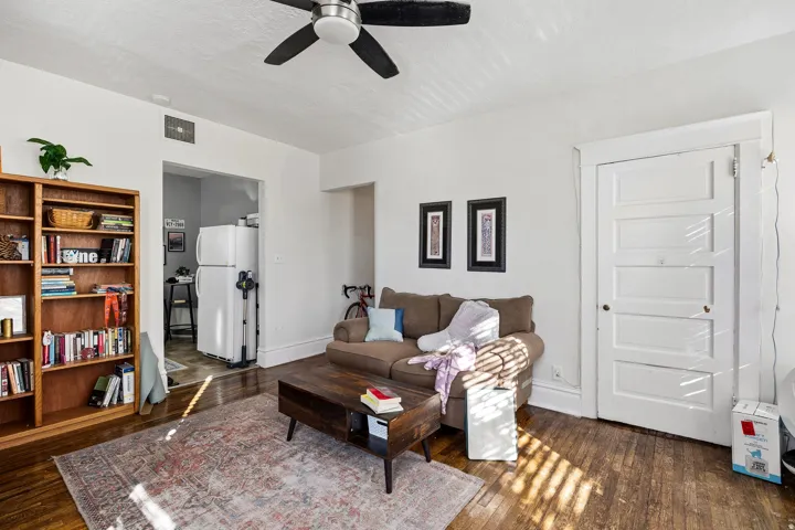 Living area with dark wood finished floors and a ceiling fan