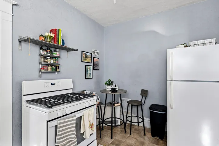 Kitchen with white appliances, open shelves, and a textured wall