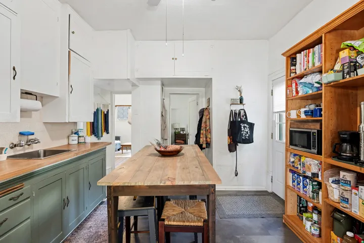 Kitchen with green cabinets, white cabinets, tasteful backsplash, stainless steel microwave, and wood counters