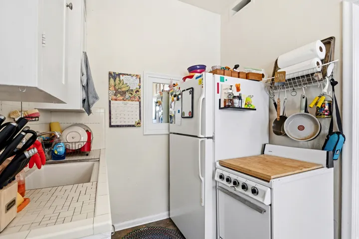 Kitchen with tile counters, white cabinets, and freestanding refrigerator