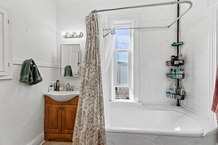 Full bathroom with shower / tub combo, vanity, and a textured wall