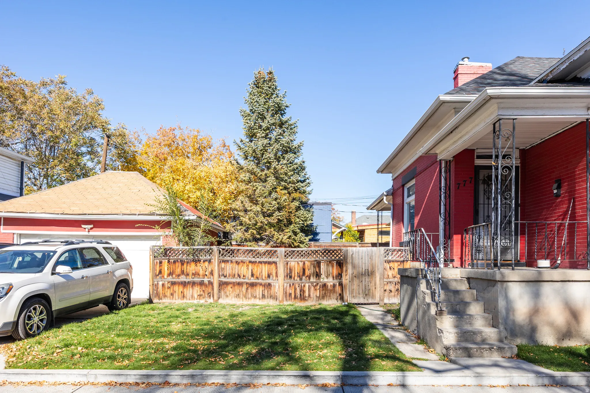 View of property exterior featuring brick siding, a chimney, covered porch, and a garage