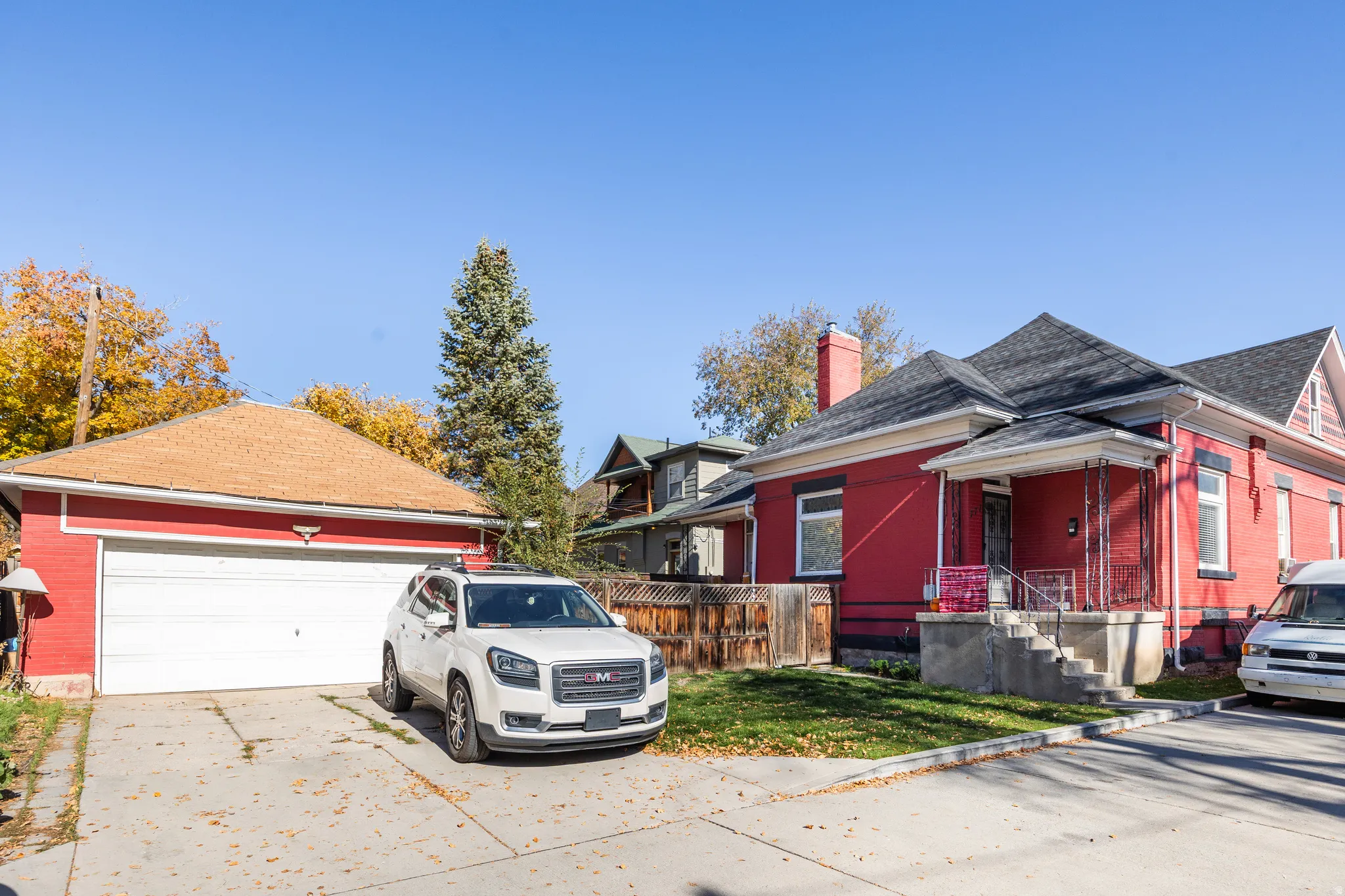 View of side of home featuring a chimney, a garage, an outdoor structure, driveway, and roof with shingles