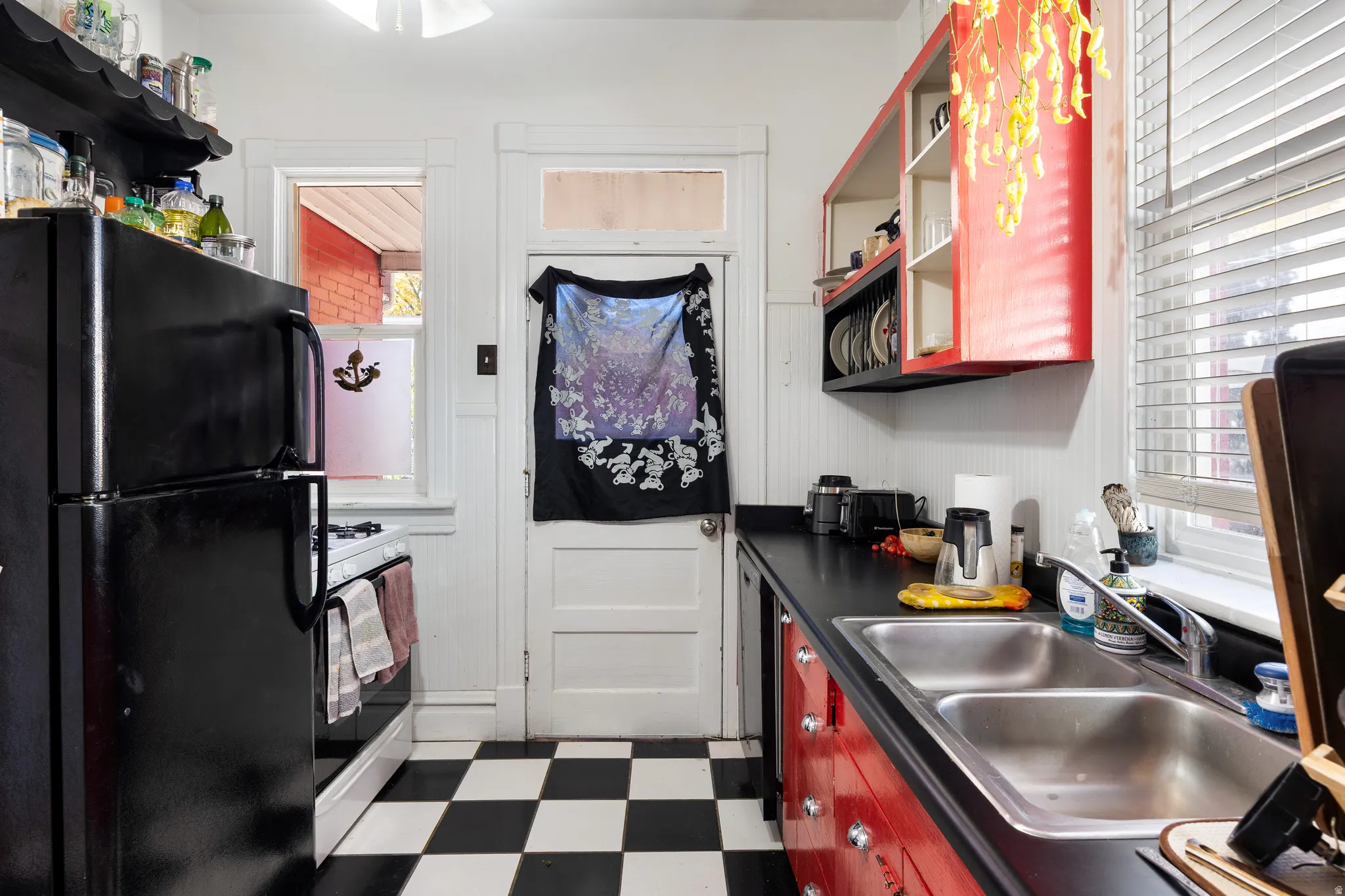 Kitchen featuring open shelves, dark flooring, freestanding refrigerator, dark countertops, and gas range gas stove