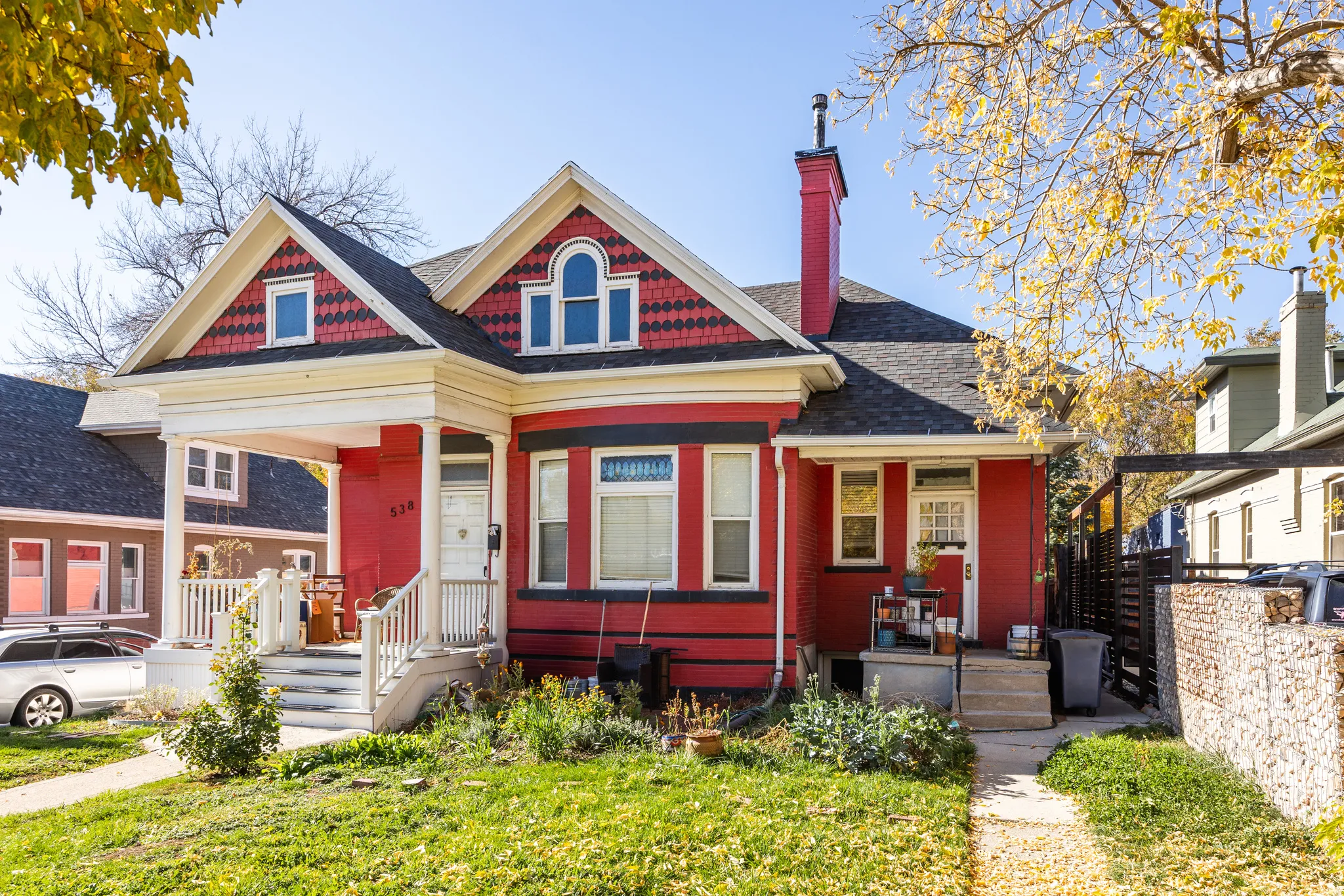 Victorian-style house with a chimney, a porch, a shingled roof, and a front yard