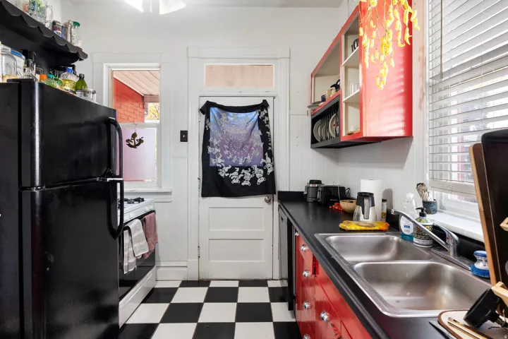 Kitchen featuring open shelves, dark flooring, freestanding refrigerator, dark countertops, and gas range gas stove