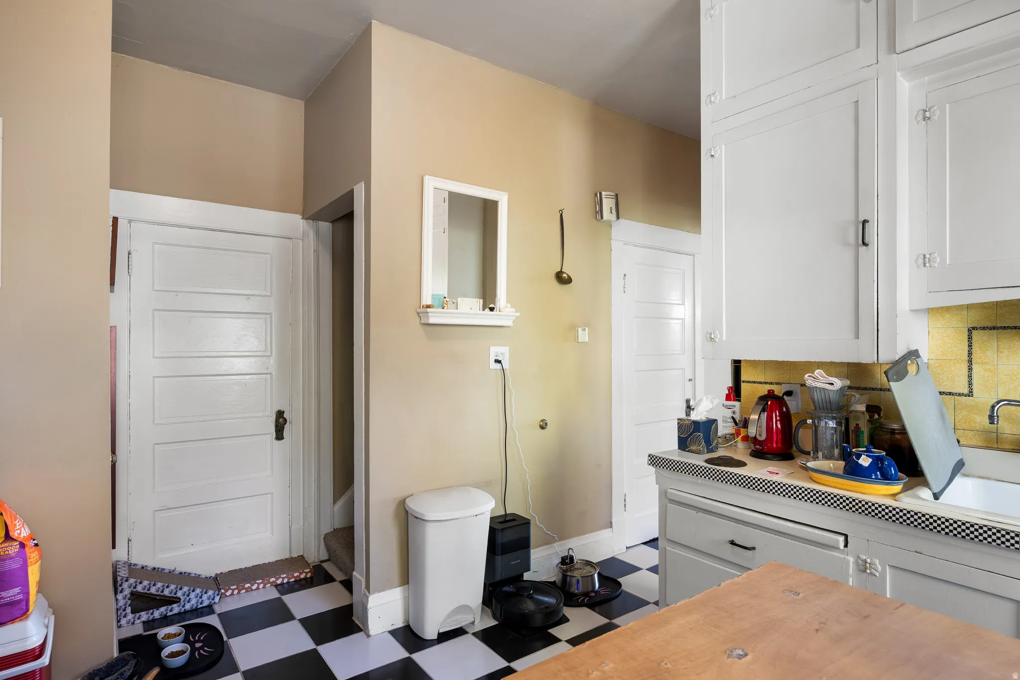 Kitchen with tile patterned floors, tasteful backsplash, light countertops, and white cabinets