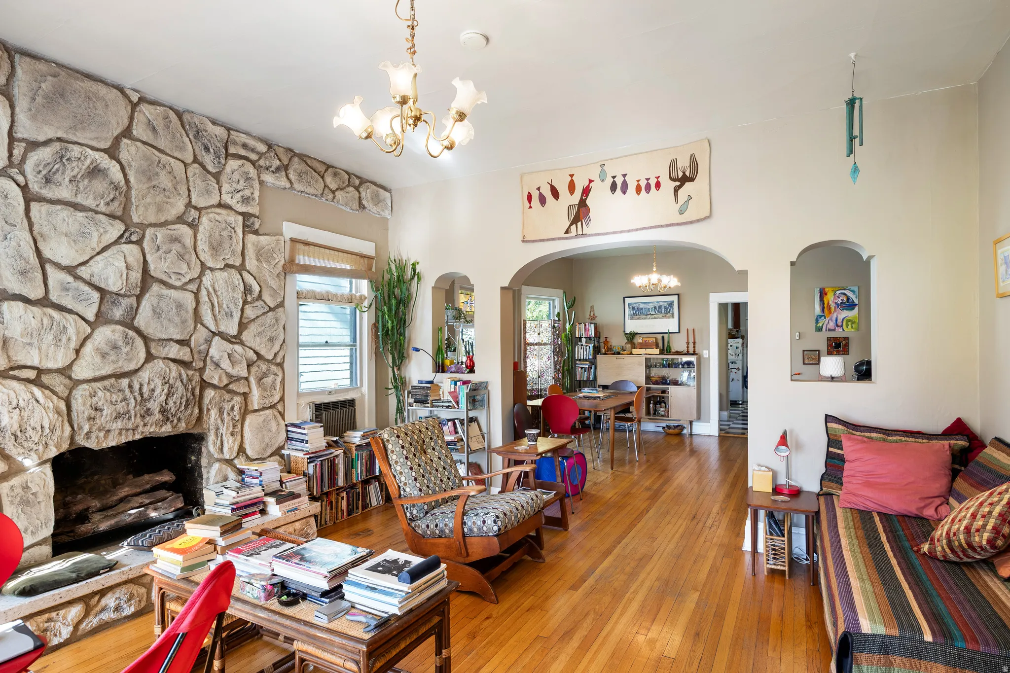 Living room with a chandelier, arched walkways, wood-type flooring, and a fireplace