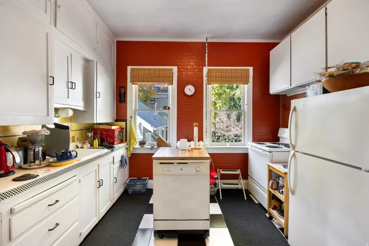 Kitchen featuring white appliances, white cabinets, and light countertops