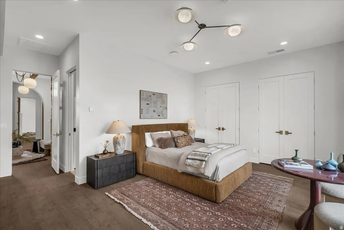Bedroom featuring arched walkways, multiple closets, dark wood-style flooring, and recessed lighting