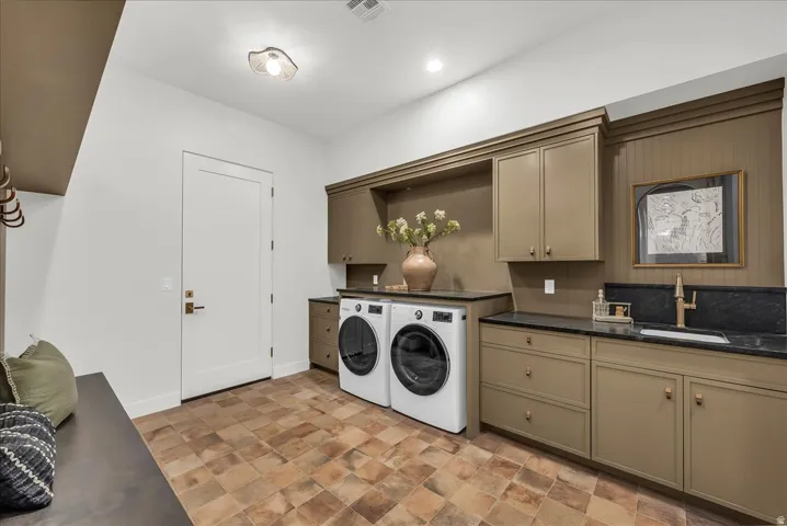 Laundry area featuring cabinet space, washing machine and clothes dryer, stone finish floors, and recessed lighting