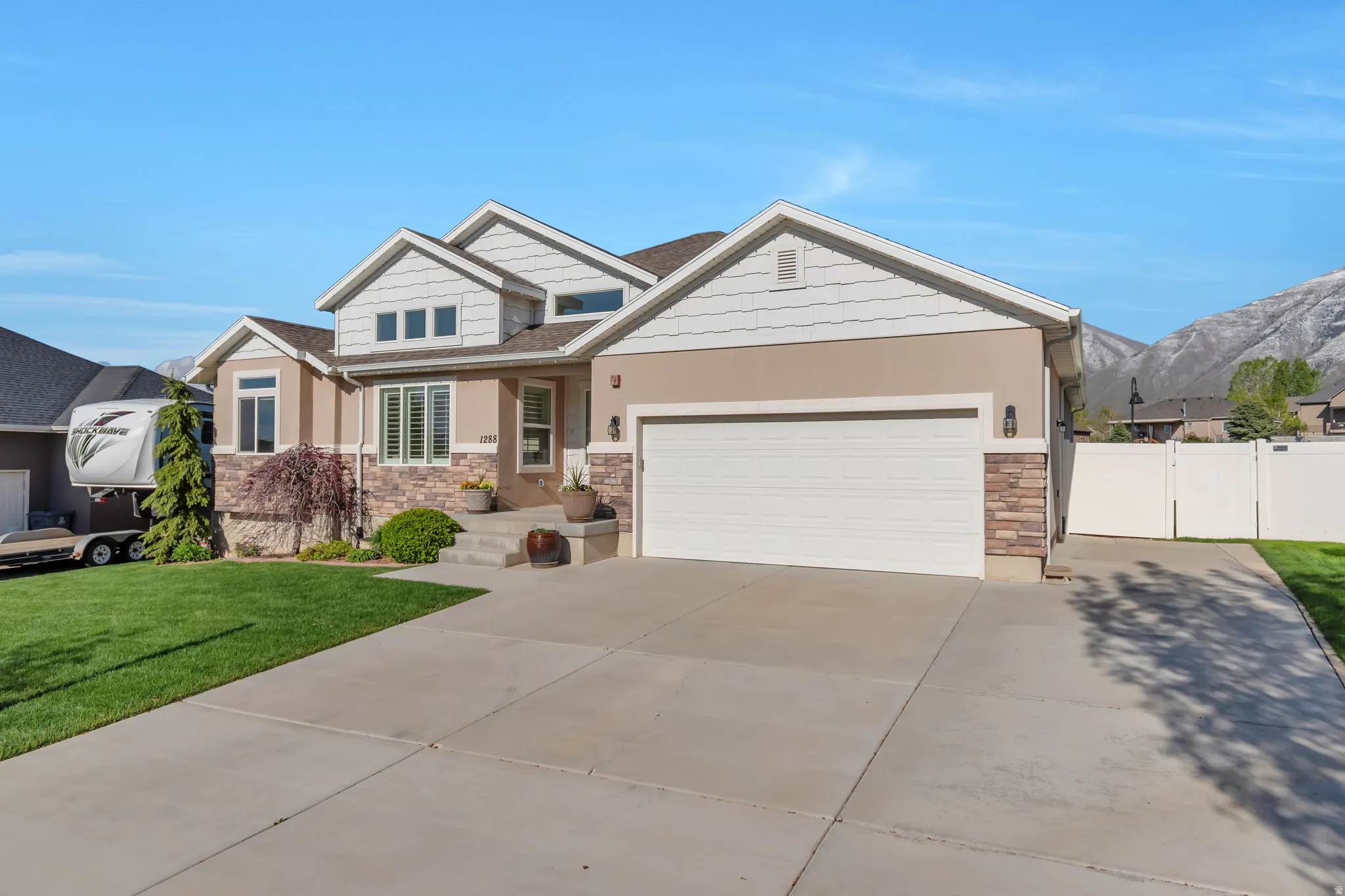 Craftsman-style house featuring stone siding, driveway, a garage, a gate, and a mountain view