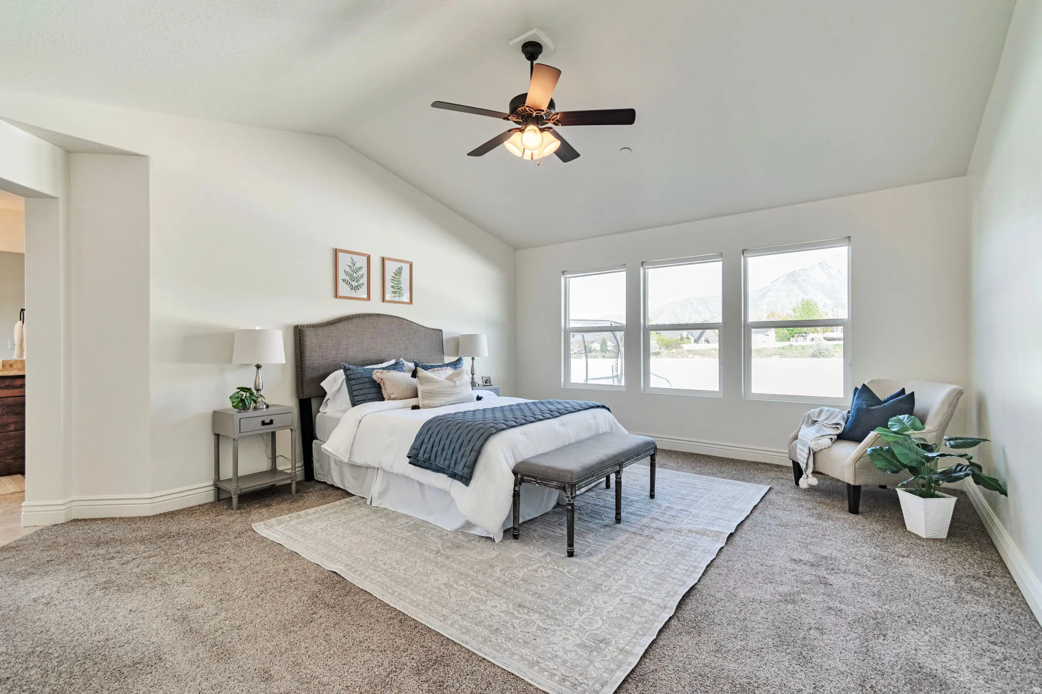 Bedroom with light colored carpet, a ceiling fan, ensuite bathroom, and a high ceiling