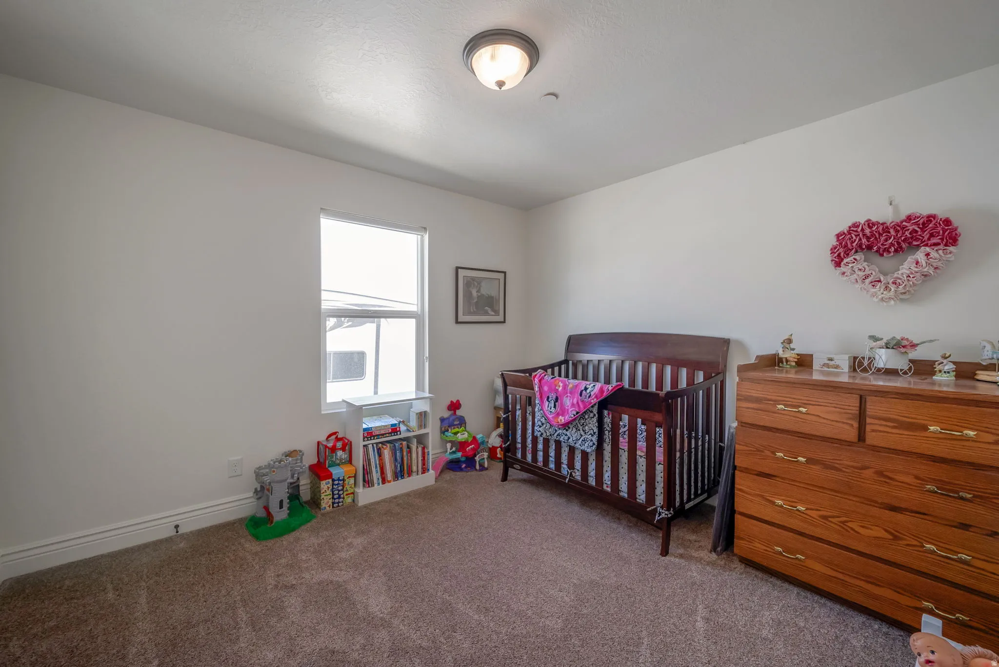 Carpeted bedroom featuring a crib and baseboards