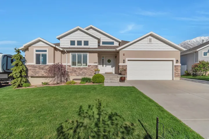 Craftsman-style home with stone siding, an attached garage, concrete driveway, and a front yard