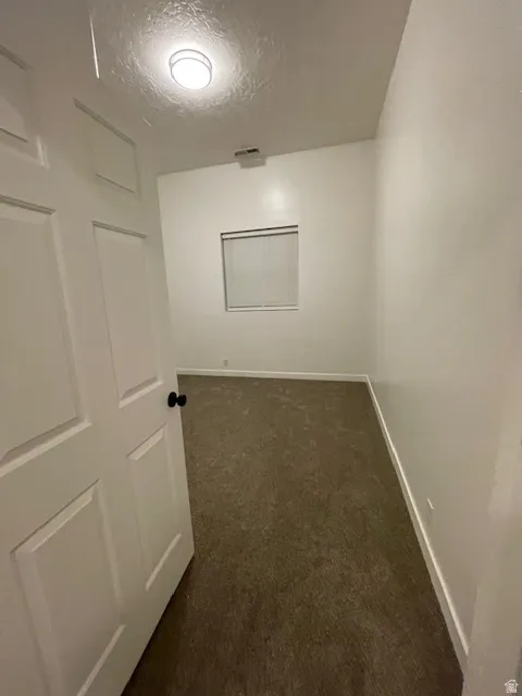 Corridor with a textured ceiling and dark carpet