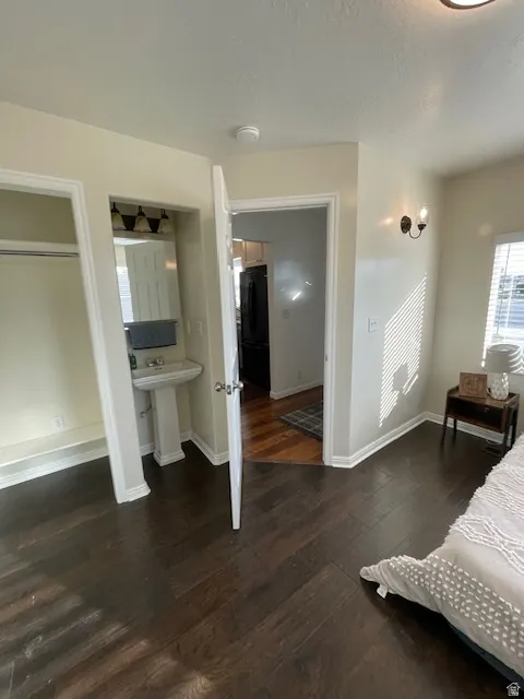 Bedroom with dark wood-style flooring and freestanding refrigerator