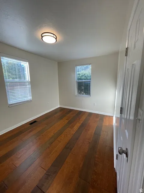 Unfurnished room with dark wood-type flooring and baseboards
