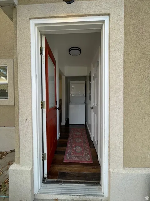 View of exterior entry featuring stucco siding and stacked washer and clothes dryer