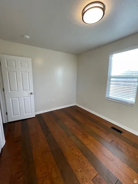 Empty room with baseboards and dark wood-style floors