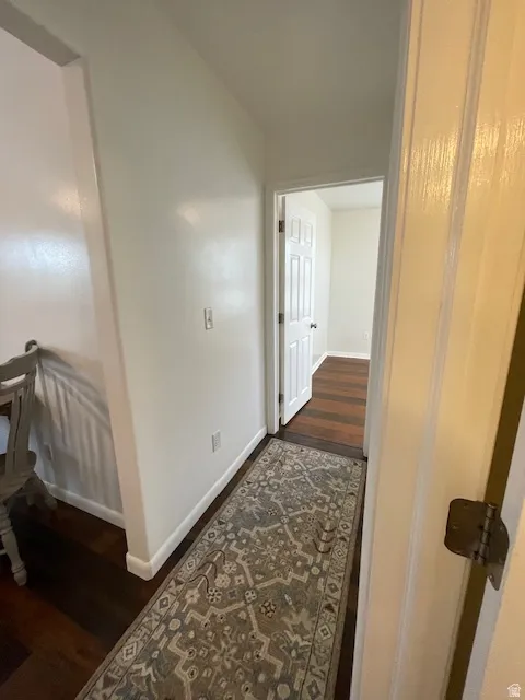 Hall with dark wood-style floors and baseboards