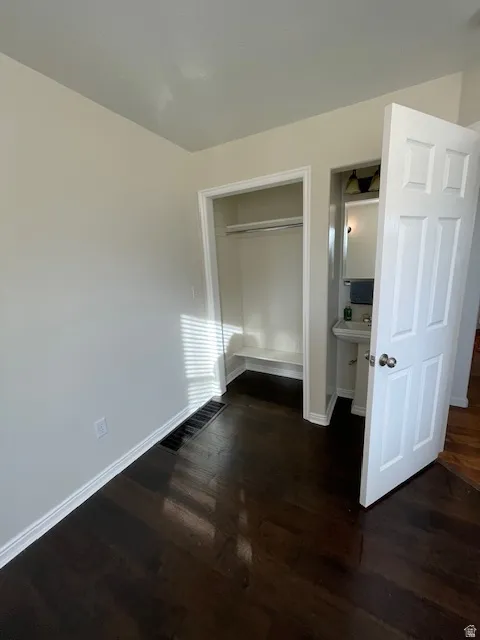 Unfurnished bedroom with dark wood-style flooring and a closet
