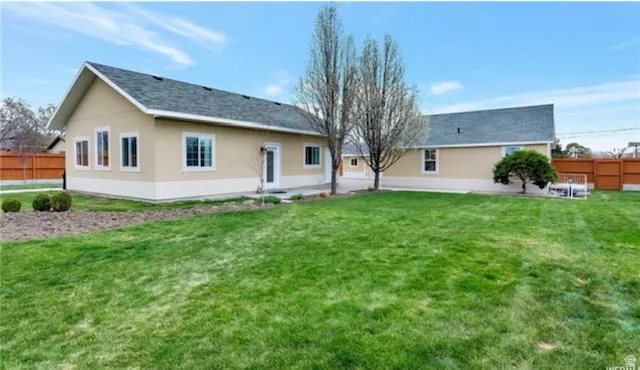 Back of property with a fenced backyard, a patio area, and stucco siding