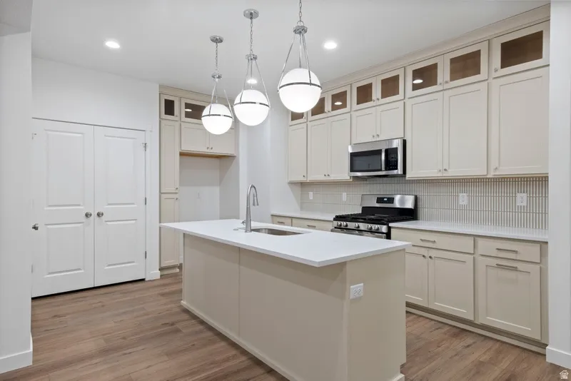 Kitchen featuring appliances with stainless steel finishes, pendant lighting, backsplash, glass insert cabinets, and recessed lighting