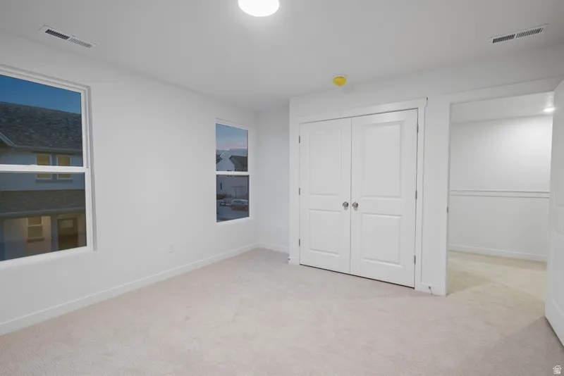 Unfurnished bedroom with light carpet and a closet
