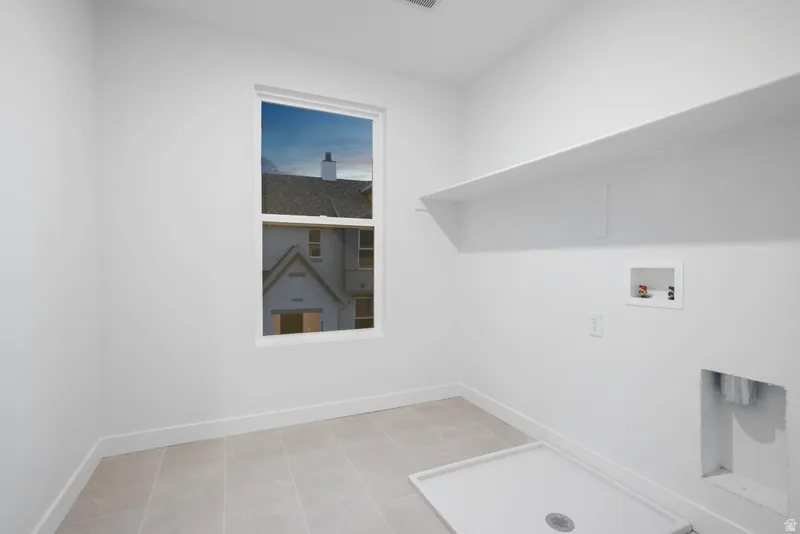 Laundry room with hookup for a washing machine and light tile patterned floors