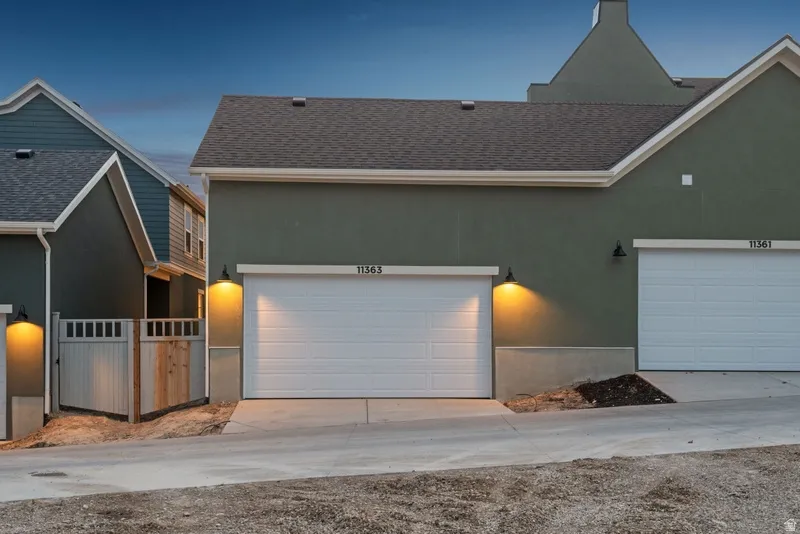 View of front of home featuring a shingled roof, driveway, and stucco siding