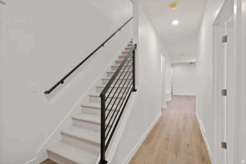 Staircase featuring wood finished floors and recessed lighting