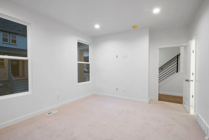 Unfurnished room featuring stairs, light colored carpet, and recessed lighting