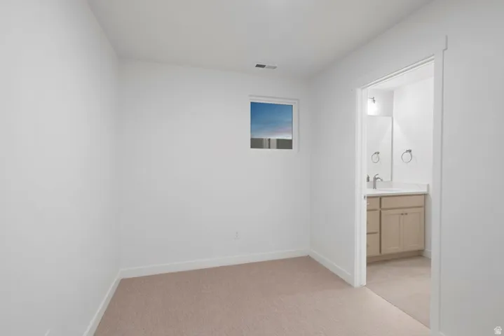 Unfurnished bedroom featuring light carpet and connected bathroom