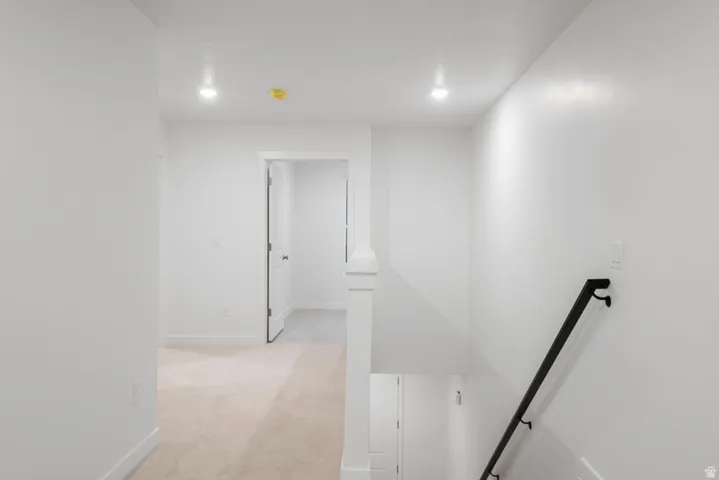 Corridor featuring light colored carpet, an upstairs landing, and recessed lighting