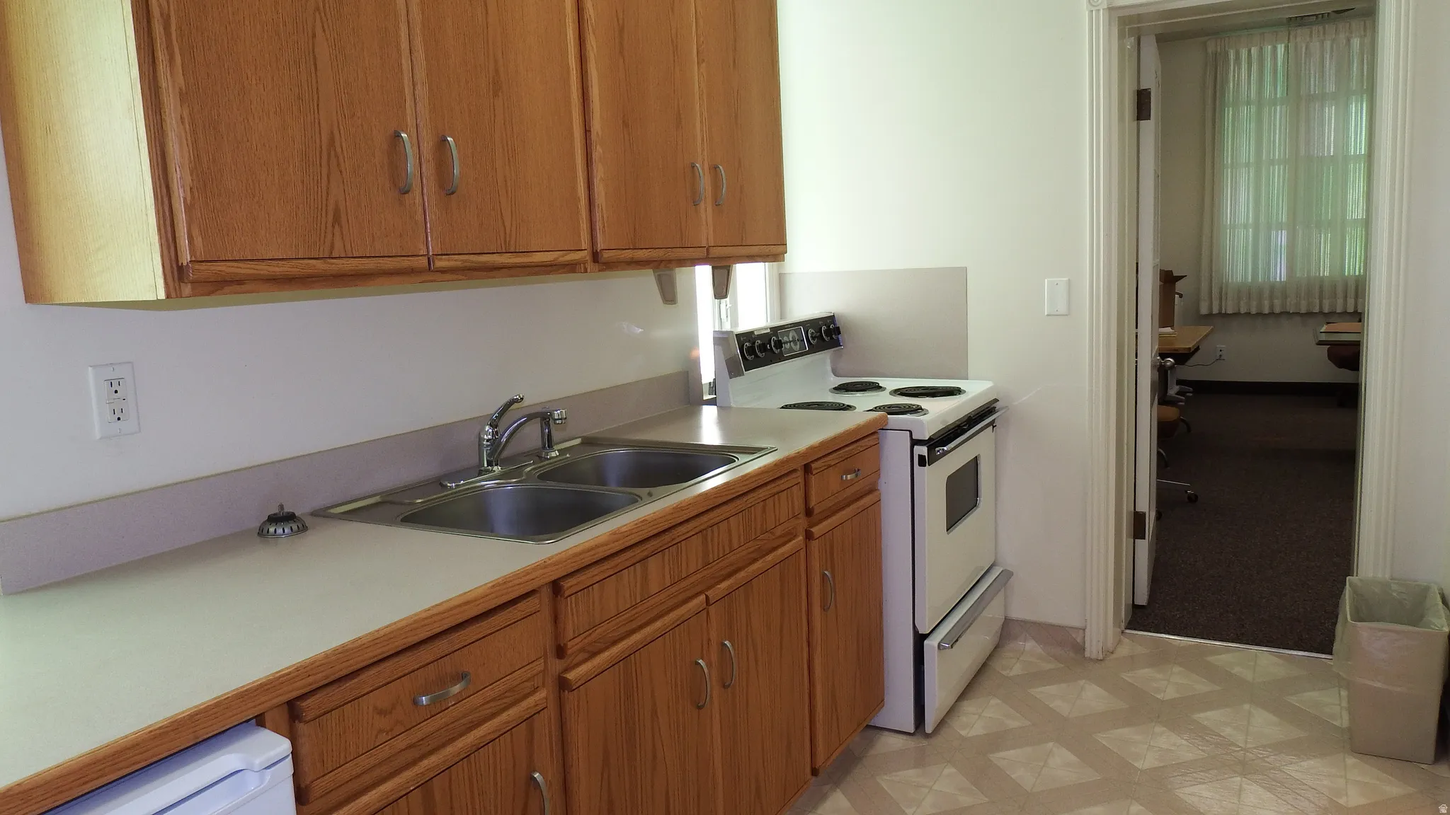 Kitchen featuring electric range, brown cabinetry, light countertops, and light floors