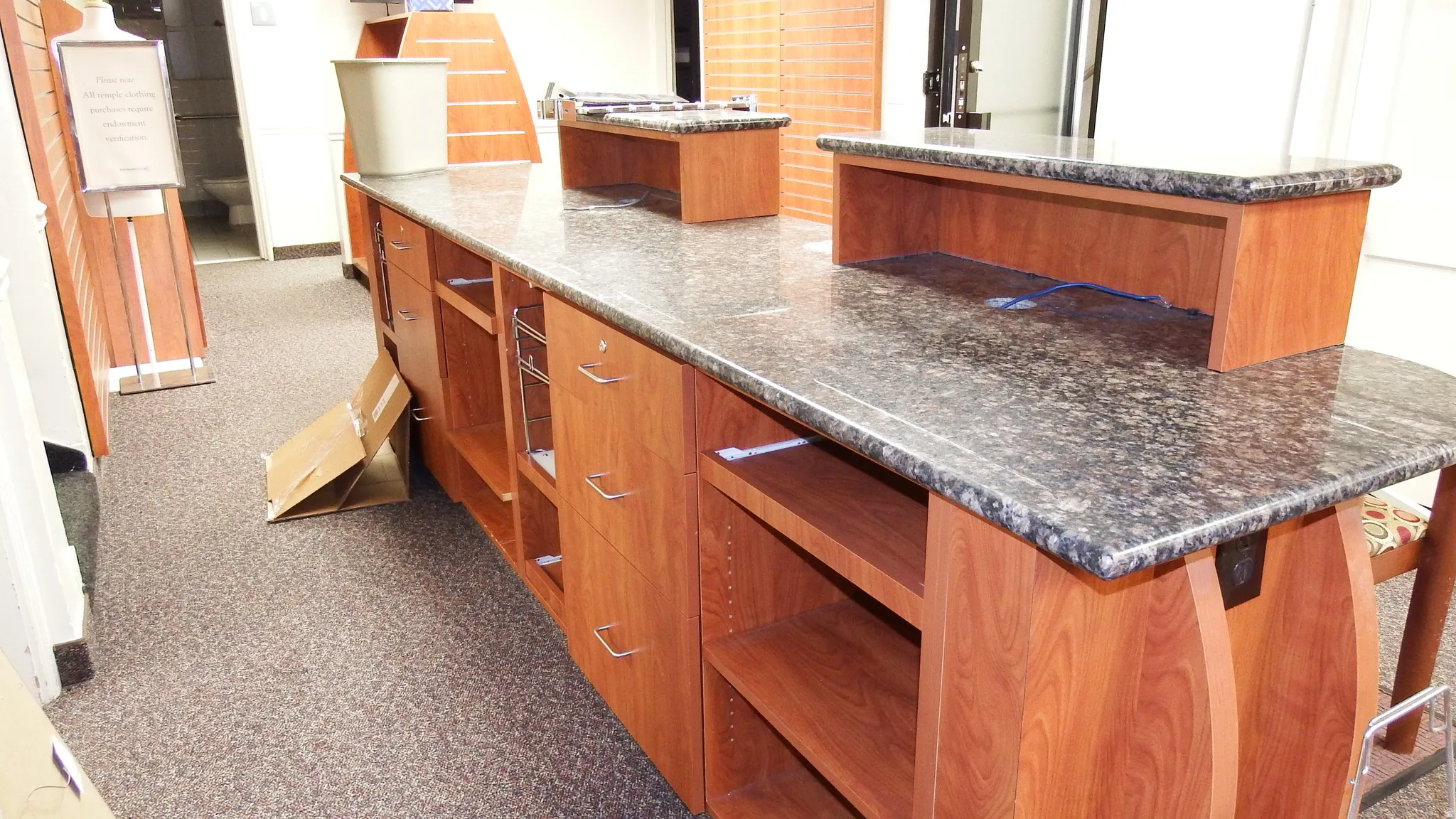 Kitchen with brown cabinetry, dark colored carpet, dark stone counters, and a center island